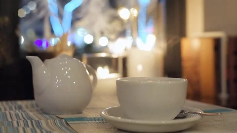 White teapot and cup on a  table  in city cafe. Stock Footage 84657641