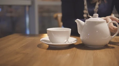 White teapot and cup on a table in city cafe. Stock Footage 88474971