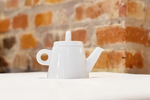 White teapot on table with brick wall background Foto stock