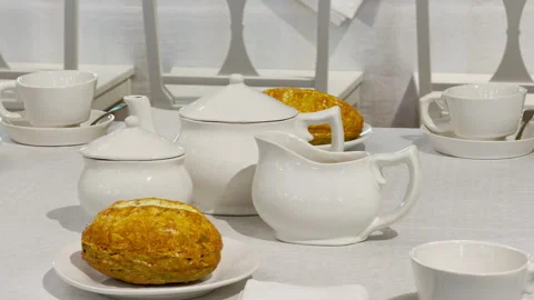 White teapots and fresh bread sit on a table Stock Footage 344974444