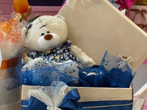 White teddy bear in open gift box with blue ribbon. Tenderness, care, innoc.. Stock Photos