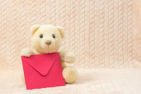 White teddy bear with a red envelope with congratulations. Stock Photos