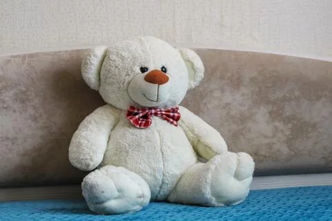 White teddy bear sitting on bed in children room interior, cozy nursery atm.. Stock Photos