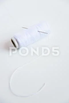 White thread and sewing needle on white background with space for text. Minimal Stock Photos