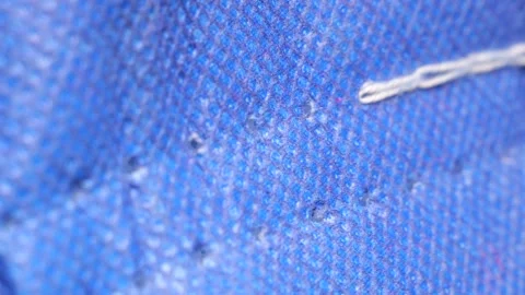 White thread pulling through blue fabric in slow motion Stock Footage 311128858