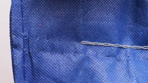 White thread pulling through blue fabric in slow motion Stock Footage 311128864