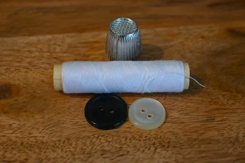White thread spool, metal thimble and buttons for home clothing repair Stock Photos