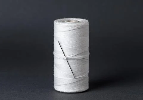 White thread spool with needle close-up on black background Stock Photos