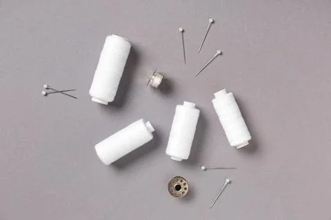 White thread spools with sewing pins on grey background Stock Photos