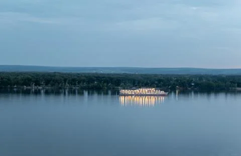 A white three decked ship lit by lights on the morning river Stock Photos