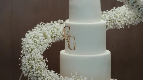White Tiered Wedding Cake With Gold Monogram Baby Breath Stock Footage 340842902
