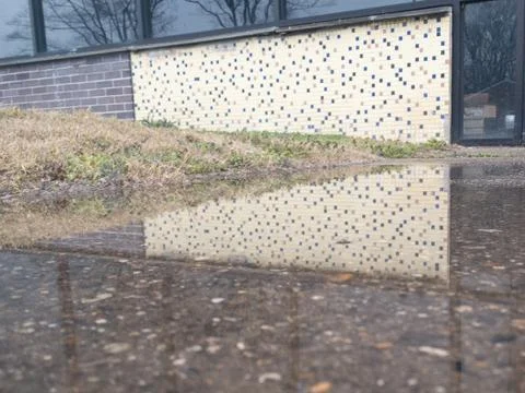 A White Tile Wall Reflecting In a Puddle Stock Photos