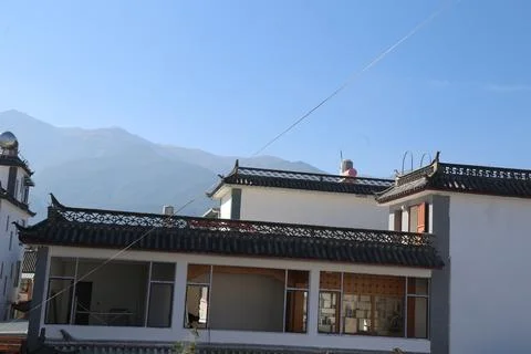 White tiled rooftops with mountain slope and power line under a clear blue sk Stock-Fotos