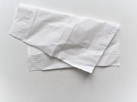 A white tissue is folded in half and laying on a white surface Stock Photos