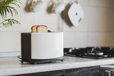White toaster with sliced bread stands on the work surface of the kitchen table Stock Photos