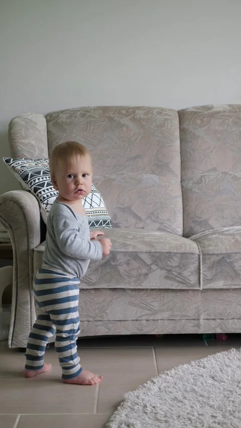 White toddler holds a sofa Stock Footage 336191283