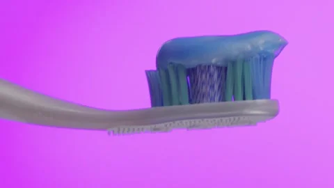 White toothbrush with blue toothpaste and pink background. Stock Footage 296578486