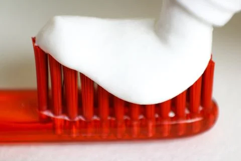 White toothpaste on an orange toothbrush. Macro. Closeup. Isolated on a white Fotos de archivo