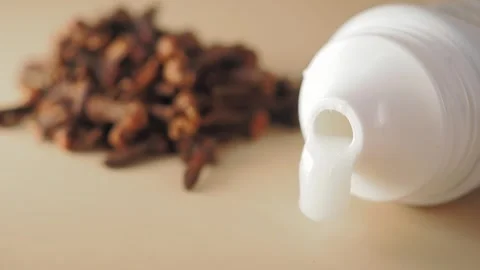 White Toothpaste Squeezing from Tube with Cloves in Background Stock Footage 335499720