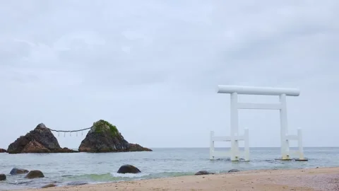 White Torii gate and sacred Meoto Iwa rocks standing in calm sea Stock Footage 338194058