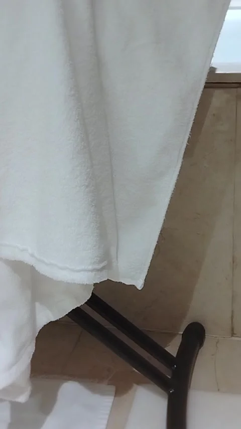 White towel draped over a black drying rack in a bathroom, showing gradual Stock Footage 338287688