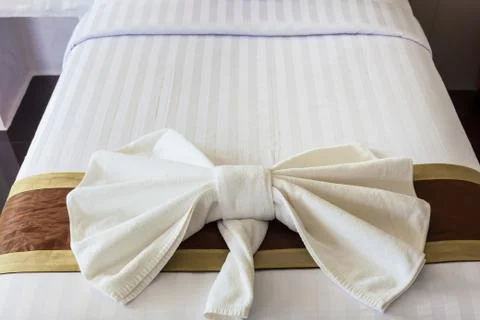 White towel folded in bow shape on bed Stock Photos