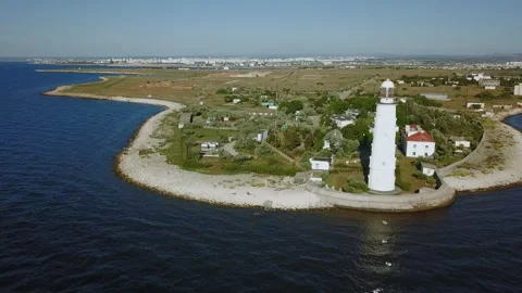 White tower of lighthouse is on sea coast at sunny Stock Footage 299680694