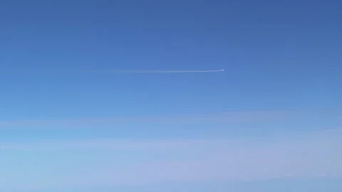 White trail from a flying airplane. Plane flying in the blue sky among cloud-Dan Stock Footage 134278154