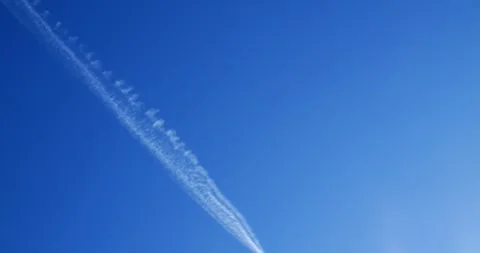 White trail gradually forming across clear blue sky, creating ethereal Stock Footage 309047903