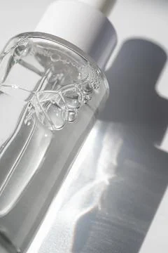 A white transparent bottle with serum in the rays of the sun. Stock Photos