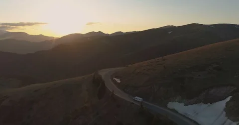 White transportation van driving on mountain road in the evening. Last sunbeams Stock Footage 129324928