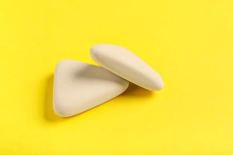 White triangular rubber erasers on yellow background Stock Photos