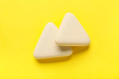 White triangular rubber erasers on yellow background Stock Photos