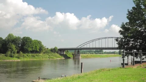 White truck traversing a bridge while anglers fish along the riverbank Stockbeeldmateriaal 291883044