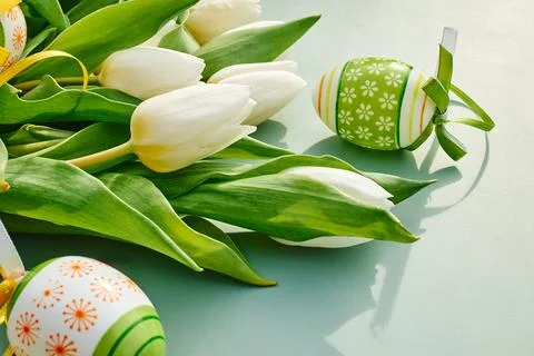 White tulips and easter eggs on green pastel background. Floral image with .. Stock Photos