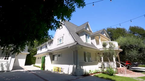 White two story house with string lights under a blue sky Stock Footage 345712174