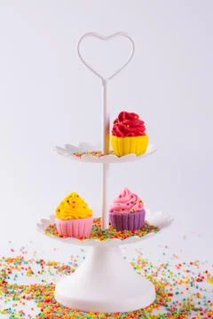 White two tier serving tray and miniature multicolored sugar cupcakes Foto stock