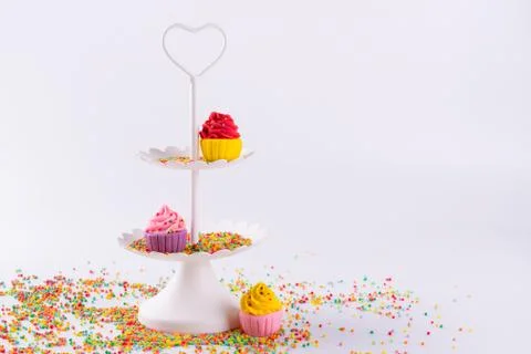 White two tier serving tray and miniature multicolored sugar cupcakes Foto stock