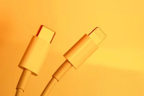 White Type-C cable and lightning, close-up on an orange background Stock Photos