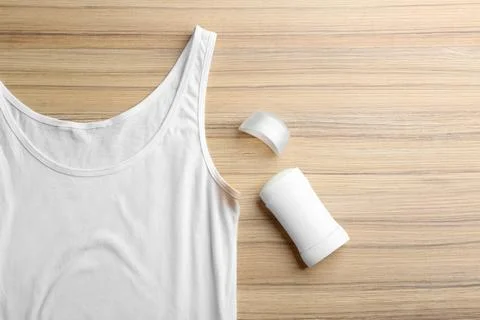 White undershirt with stain and deodorant on wooden background, top view Stock Photos
