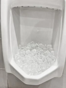 A white urinal filled with ice cubes Stock Photos