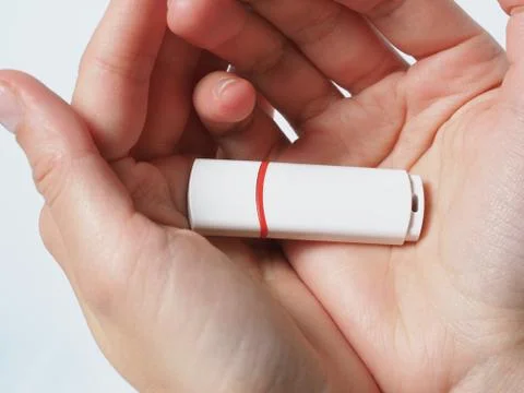 White usb flash drive isolated with red stripe in hands close up Stock Photos