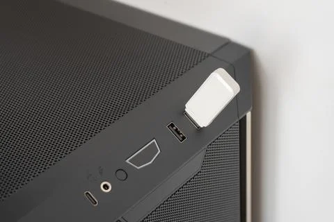 White USB flash drive plugged into computer case port on black mesh panel Stock Photos