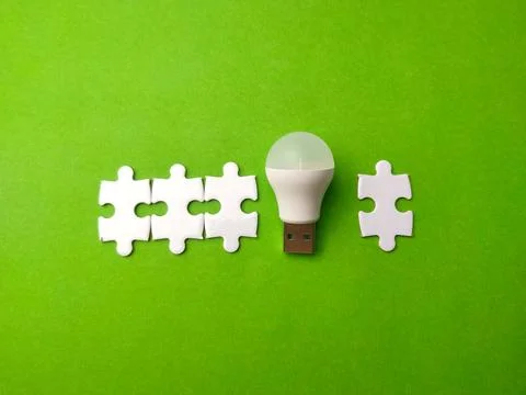 White USB LED light bulb placed between interlocking white puzzle pieces on.. 库存照片