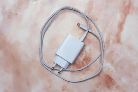 White USB smartphone charging cable and power adapter on a marble table. Stock Photos