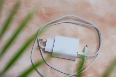 White USB smartphone charging cable and power adapter on a marble table. Stock Photos