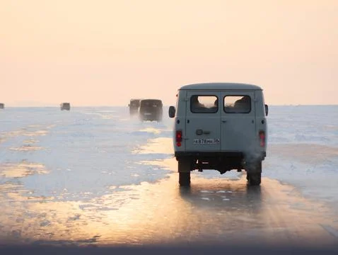 A white van is currently driving down a road covered in snow Stock Photos