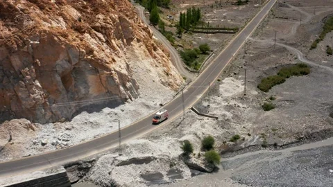 White van driving through a valley in a high mountain range Stock Footage 159992256