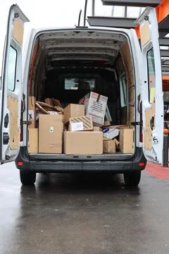 A white van is filled with boxes and is parked on a wet street Stock Photos