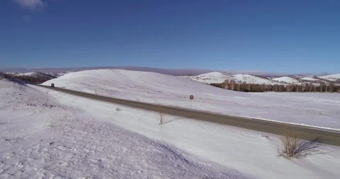 White van rides on an empty snowy road in the mountains Stock Footage 104471666
